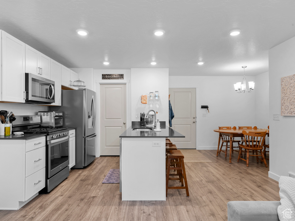 Kitchen featuring light hardwood / wood-style floors, stainless steel appliances, sink, and a breakfast bar area