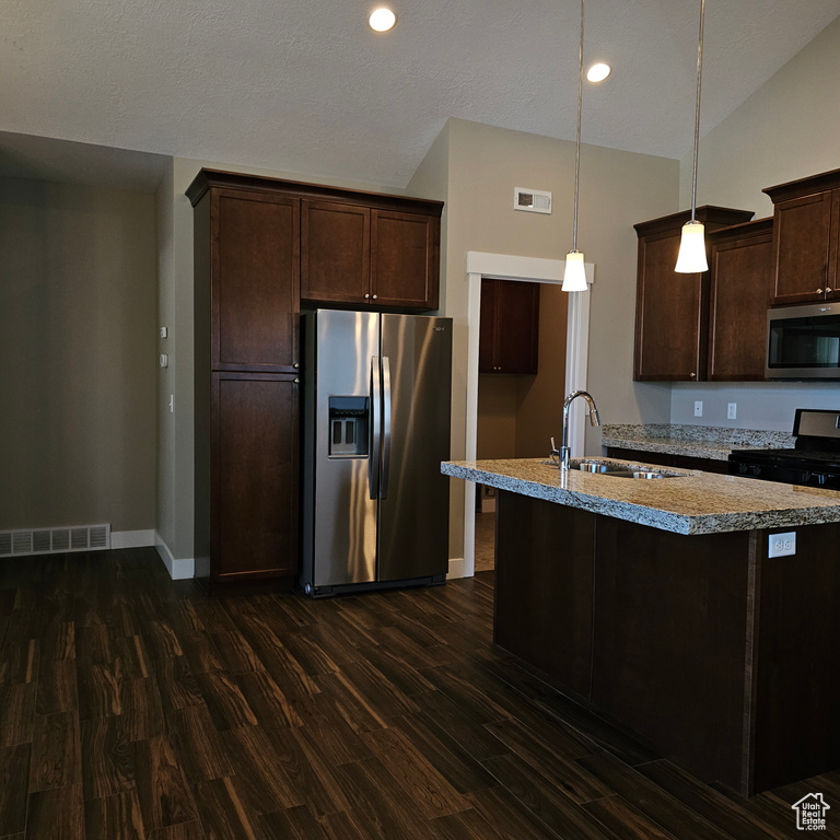 Kitchen with stainless steel appliances, vaulted ceiling, decorative light fixtures, and dark hardwood / wood-style flooring