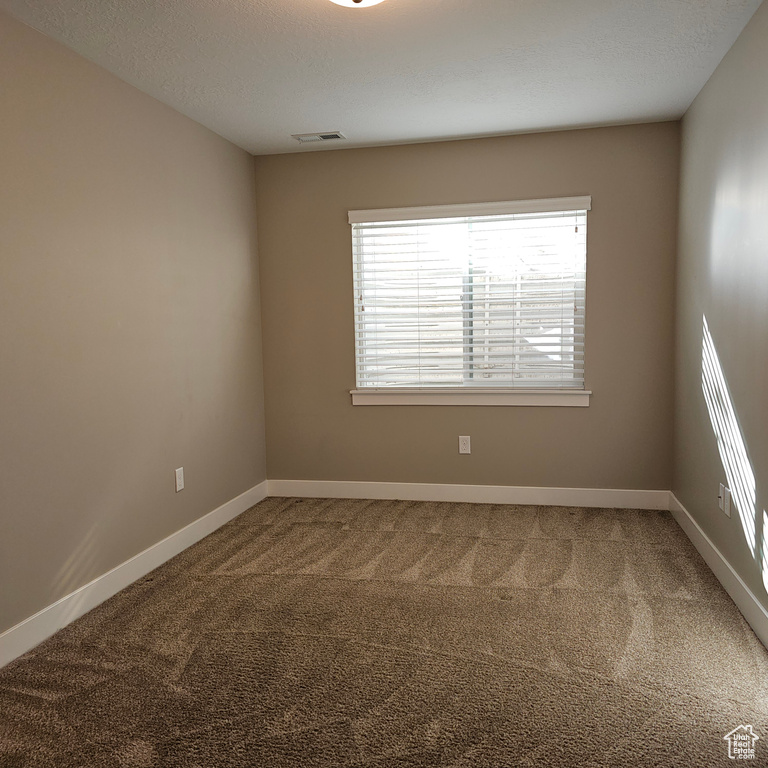 Carpeted empty room featuring a textured ceiling