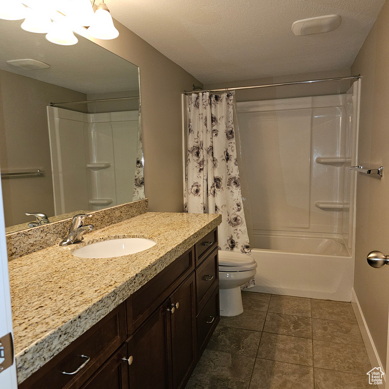 Full bathroom with vanity, shower / bath combo with shower curtain, a textured ceiling, and toilet