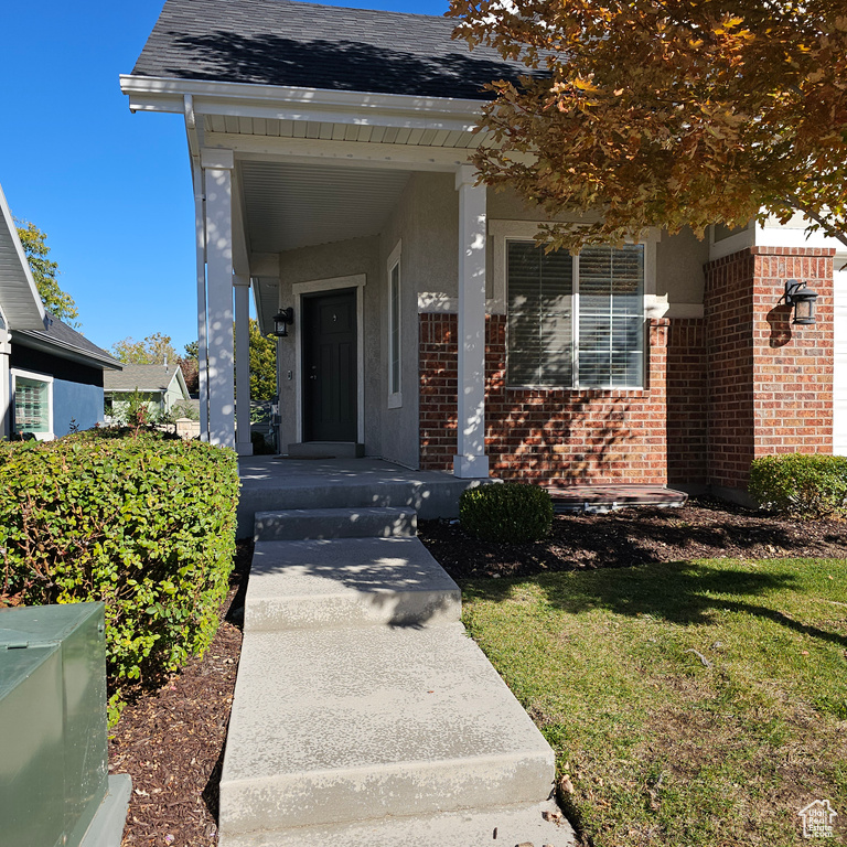 Entrance to property featuring covered porch and a lawn