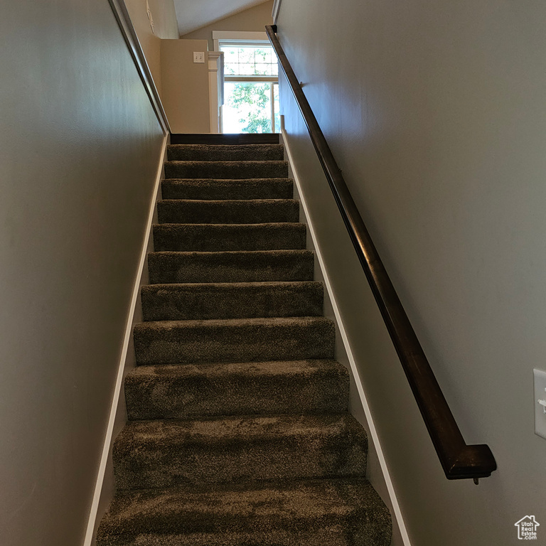 Stairs featuring vaulted ceiling and carpet floors