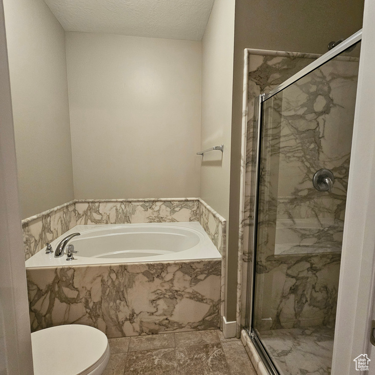 Bathroom with toilet, a textured ceiling, and plus walk in shower