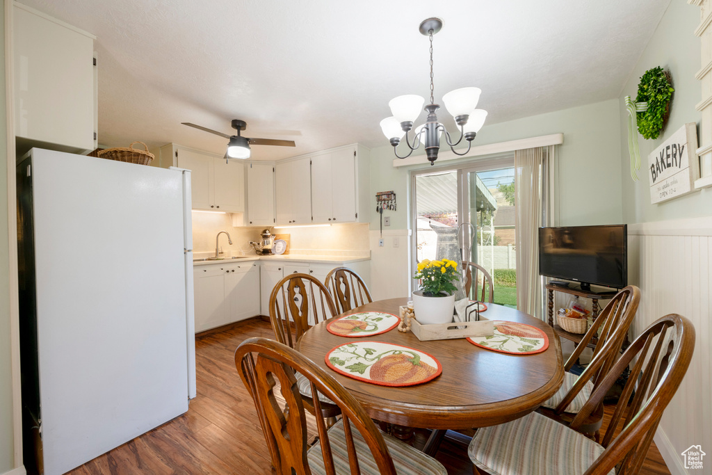 Dining room with hardwood / wood-style floors, sink, and ceiling fan with notable chandelier