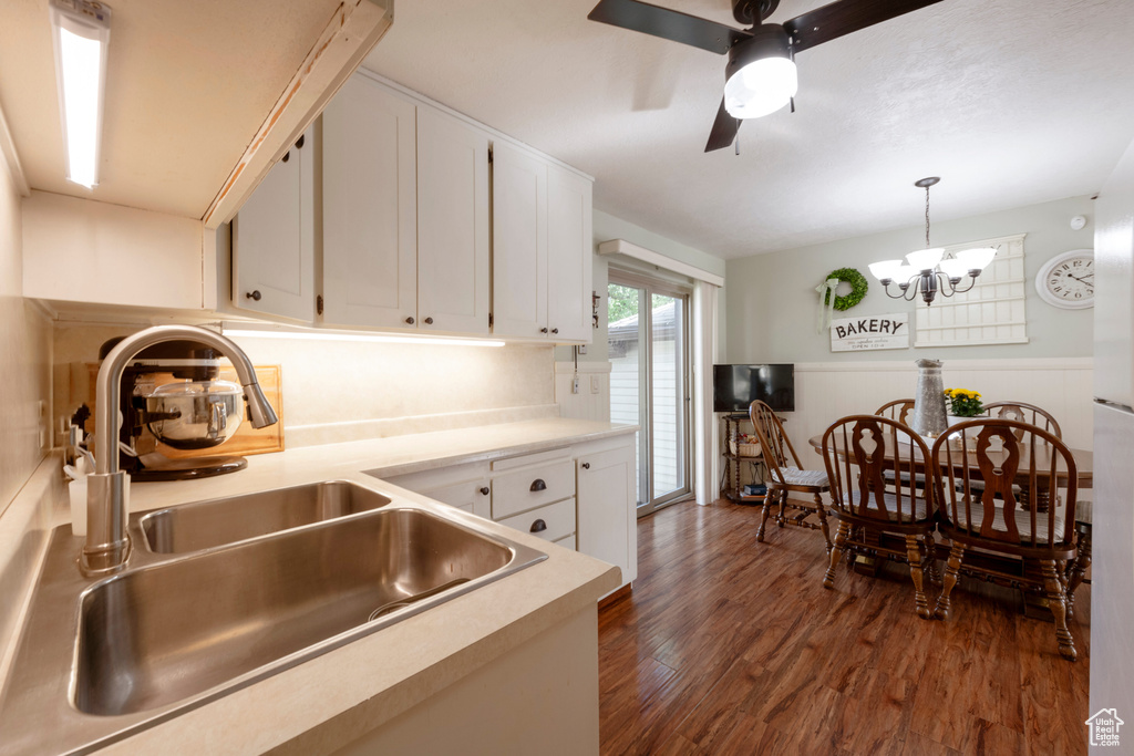 Kitchen featuring sink, pendant lighting, white cabinets, ceiling fan with notable chandelier, and dark hardwood / wood-style flooring