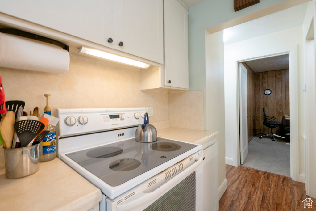 Kitchen featuring white electric range, dark hardwood / wood-style floors, and white cabinetry