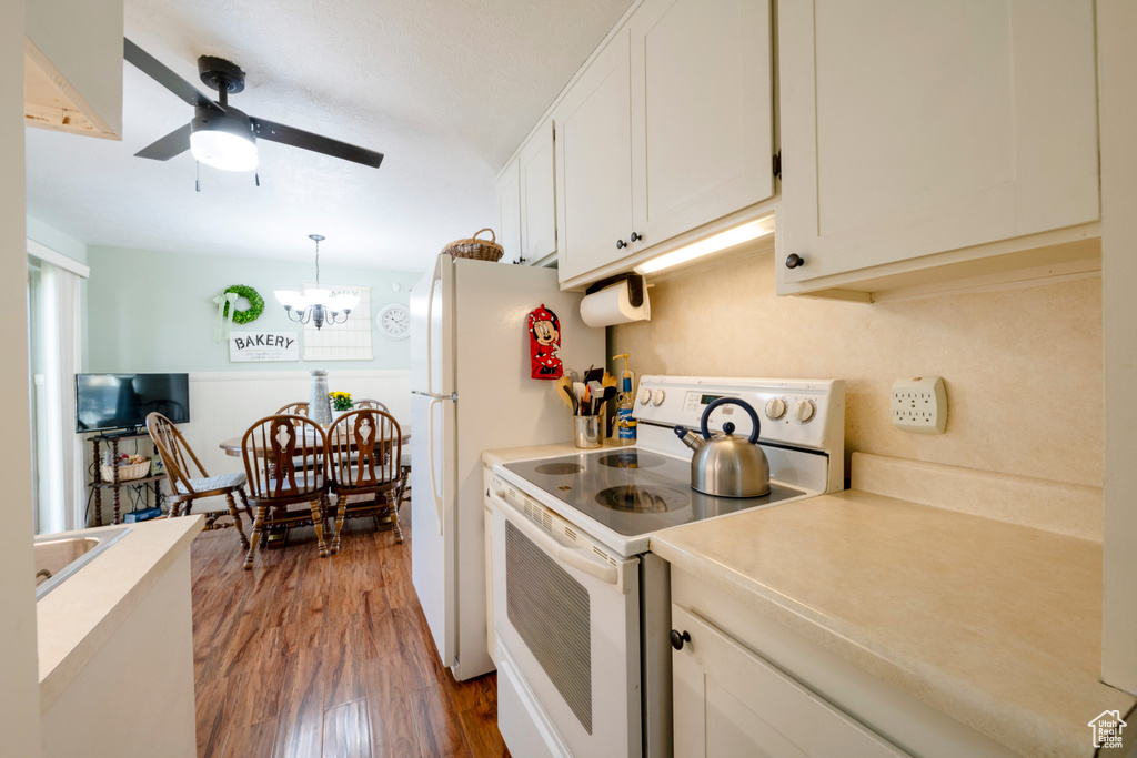 Kitchen with white appliances, white cabinetry, pendant lighting, and dark hardwood / wood-style floors