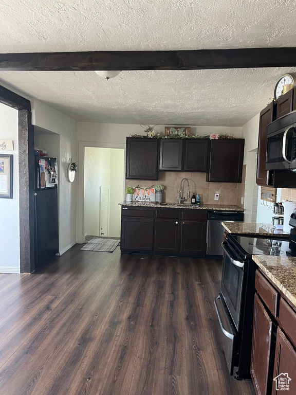 Kitchen featuring sink, beam ceiling, a textured ceiling, appliances with stainless steel finishes, and dark hardwood / wood-style flooring