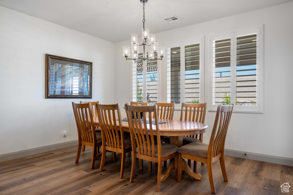 Dining room with a notable chandelier, dark hardwood / wood-style floors, and plenty of natural light