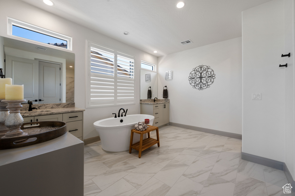 Bathroom with a wealth of natural light, vanity, and a tub