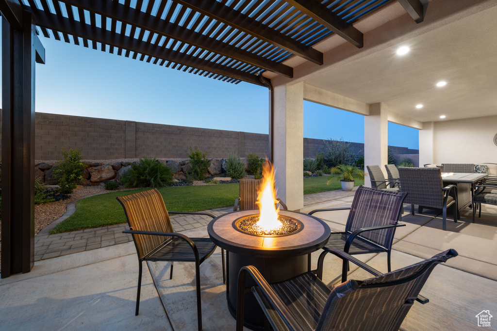 Patio terrace at dusk with a pergola and a fire pit