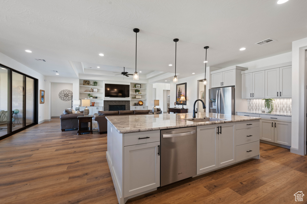 Kitchen featuring sink, appliances with stainless steel finishes, white cabinets, and an island with sink