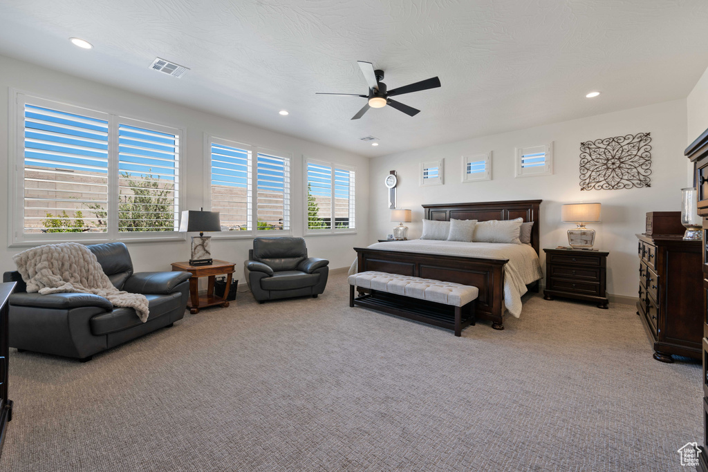 Bedroom with light carpet, multiple windows, and ceiling fan