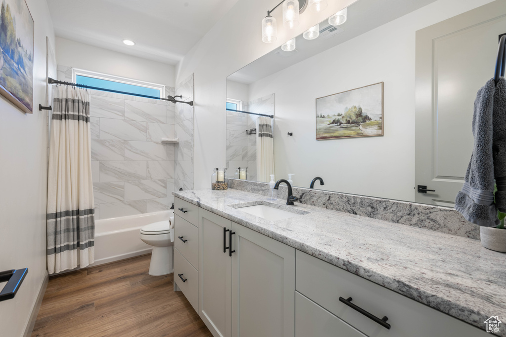 Full bathroom featuring vanity, hardwood / wood-style floors, toilet, and shower / bathtub combination with curtain