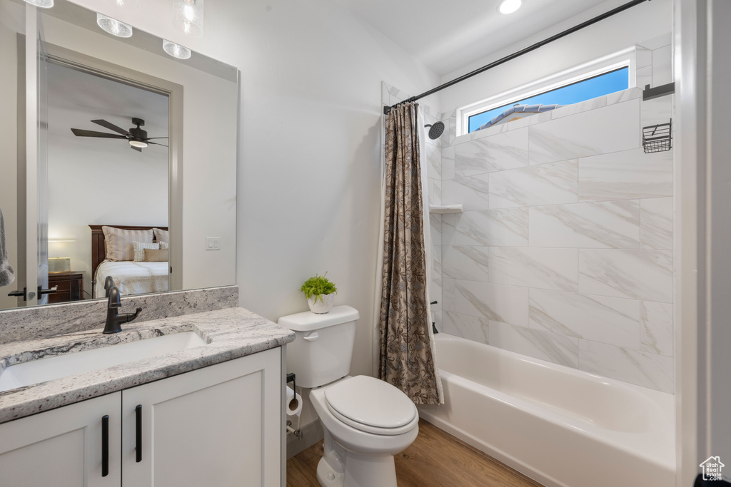 Full bathroom with hardwood / wood-style flooring, toilet, shower / tub combo, vanity, and ceiling fan