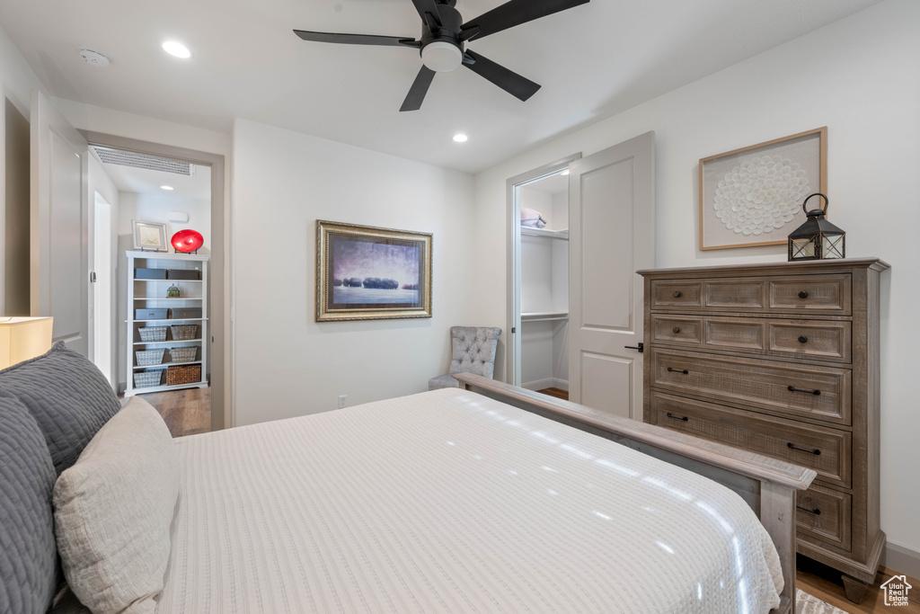 Bedroom featuring a walk in closet, hardwood / wood-style flooring, and ceiling fan