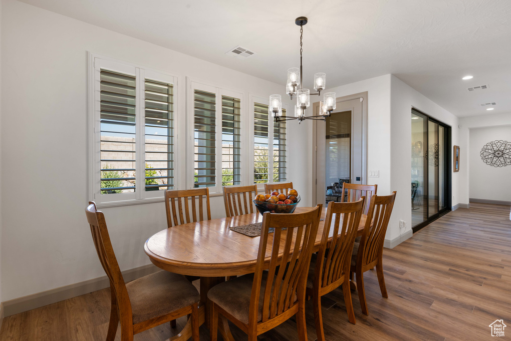 Dining room with a wealth of natural light, an inviting chandelier, and hardwood / wood-style floors