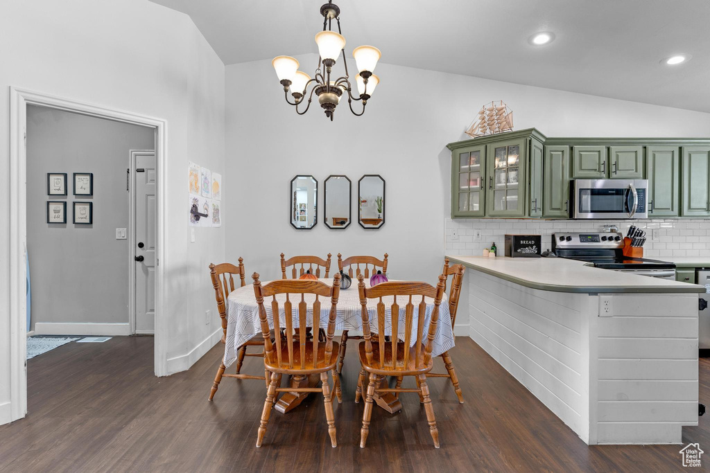 Dining area with dark hardwood / wood-style floors, a chandelier, and vaulted ceiling