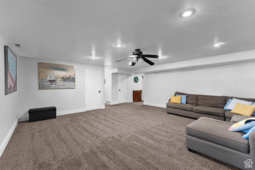 Carpeted living room with a textured ceiling and ceiling fan