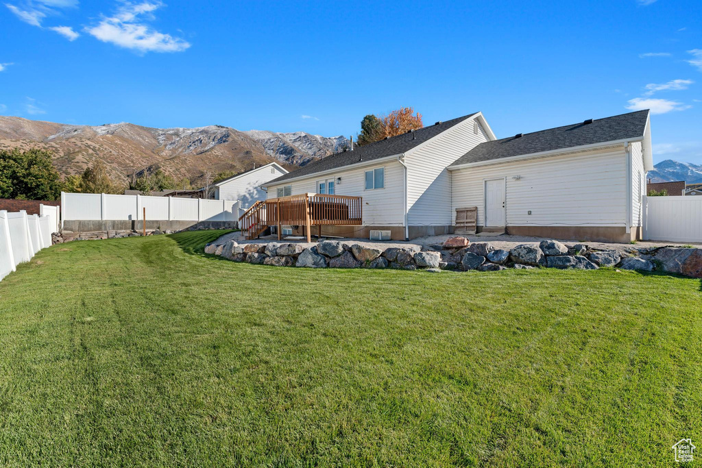 Back of property with a yard and a deck with mountain view