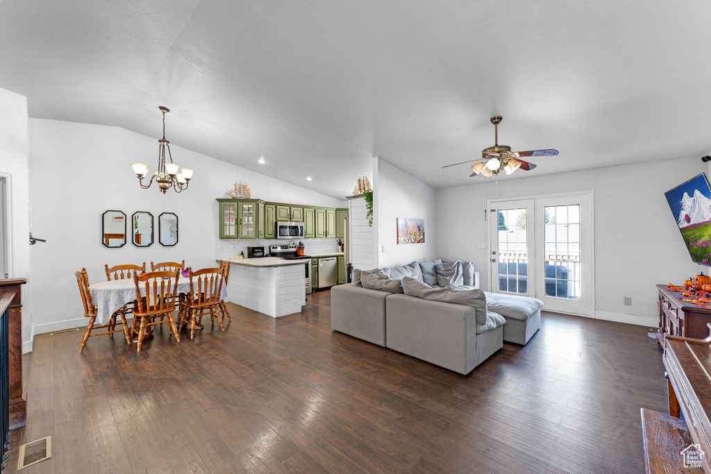 Living room with dark wood-type flooring, lofted ceiling, and ceiling fan with notable chandelier