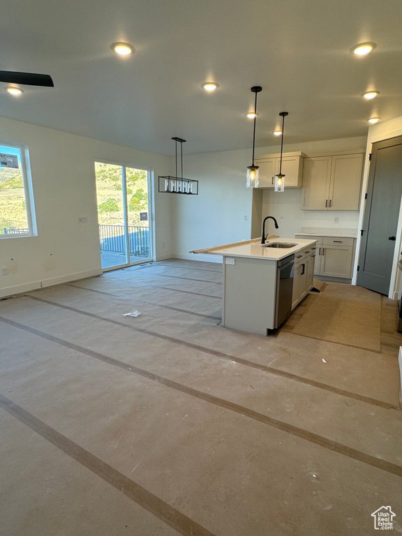 Kitchen featuring a kitchen island with sink, sink, hanging light fixtures, and plenty of natural light