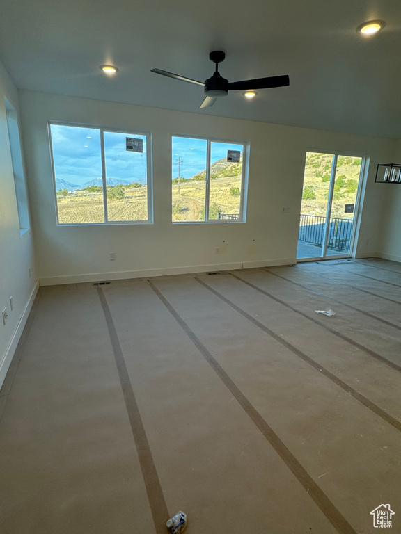 Unfurnished room with ceiling fan, plenty of natural light, and concrete flooring