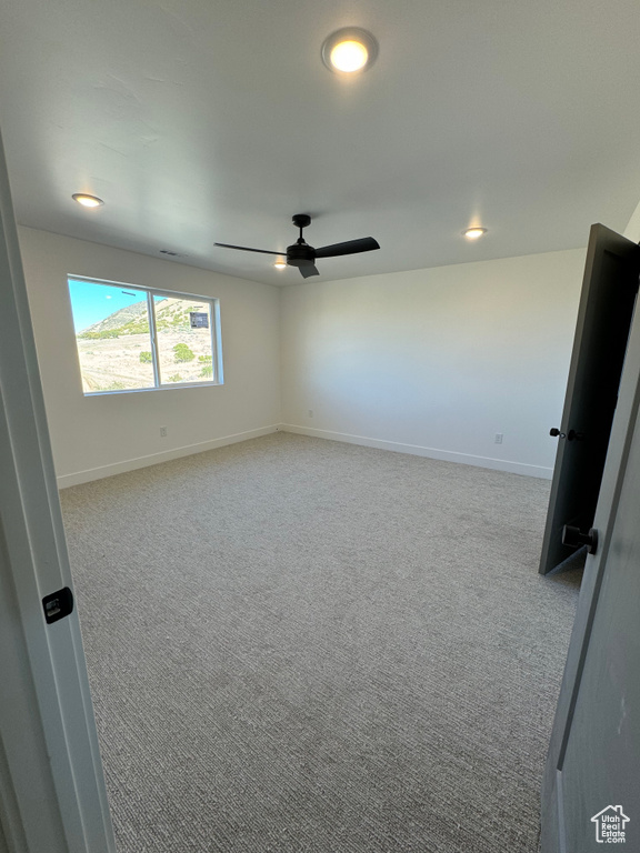 Carpeted empty room featuring ceiling fan