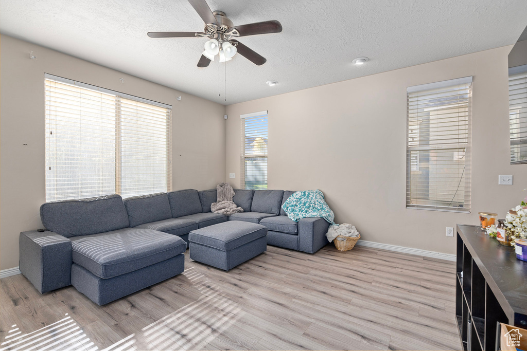 Living room featuring light hardwood / wood-style flooring, a textured ceiling, and ceiling fan