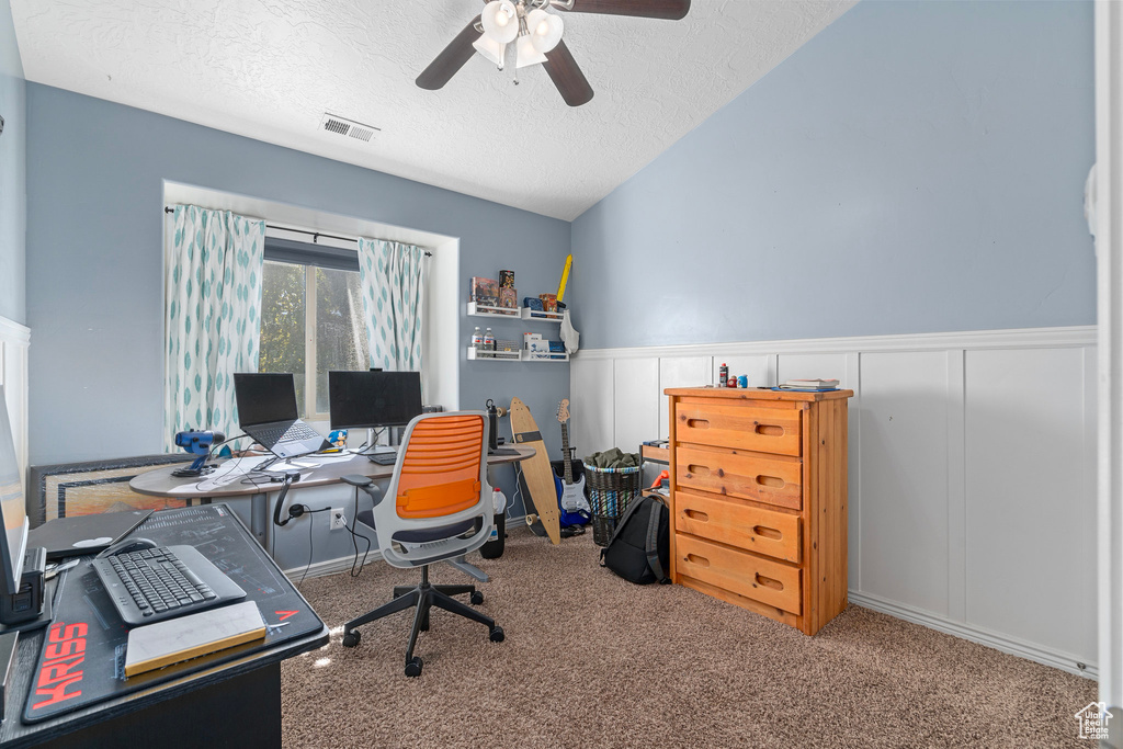 Carpeted office with a textured ceiling, vaulted ceiling, and ceiling fan