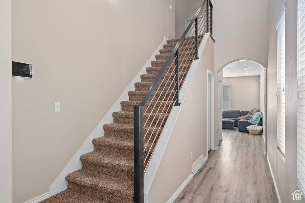 Staircase featuring hardwood / wood-style flooring and a towering ceiling