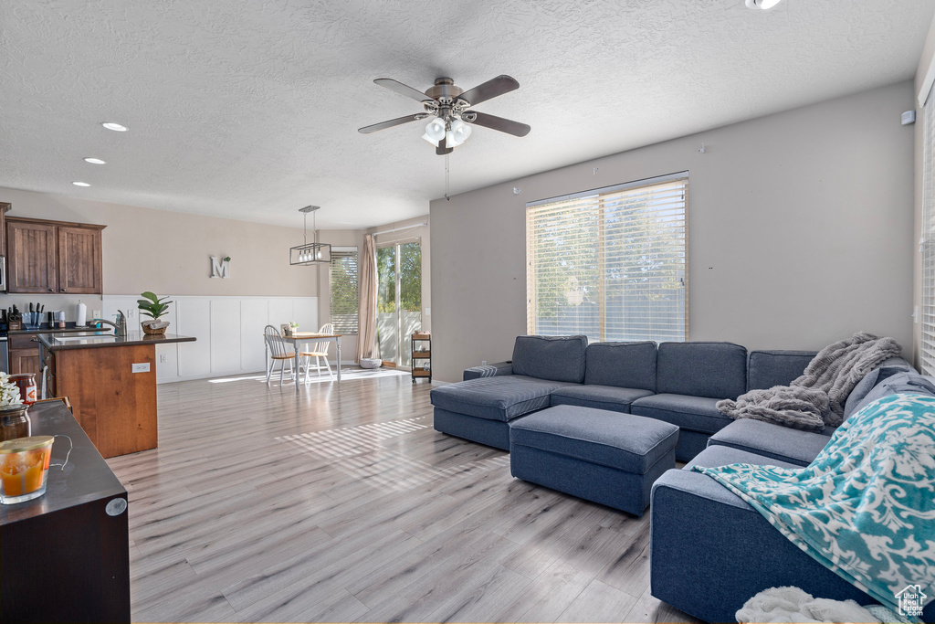 Living room featuring light hardwood / wood-style flooring, a textured ceiling, and ceiling fan