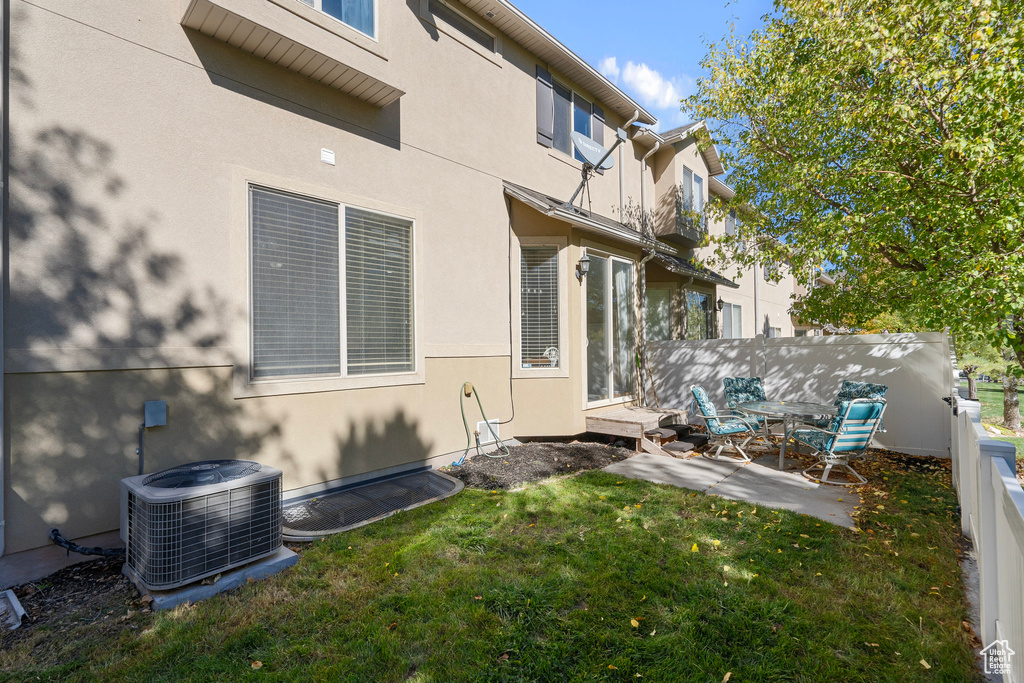 Rear view of house with a patio, a lawn, and central AC unit