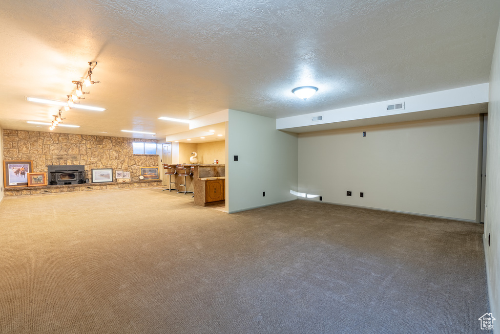 Basement featuring bar, carpet flooring, track lighting, and a textured ceiling