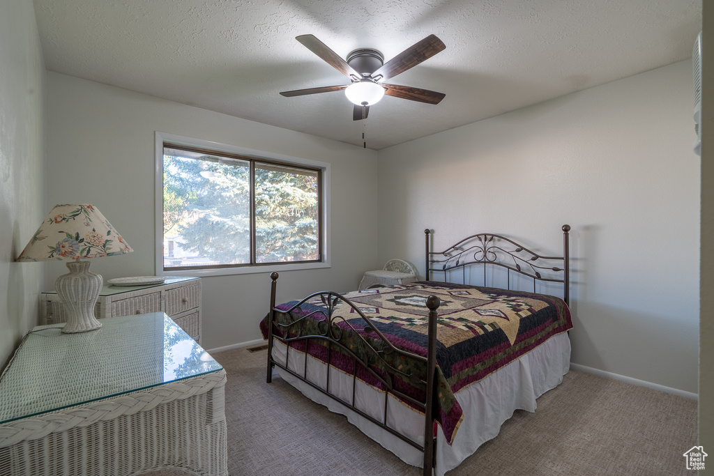 Carpeted bedroom featuring a textured ceiling and ceiling fan