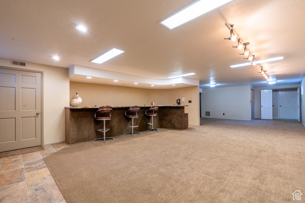 Kitchen featuring a breakfast bar area, kitchen peninsula, light colored carpet, and rail lighting