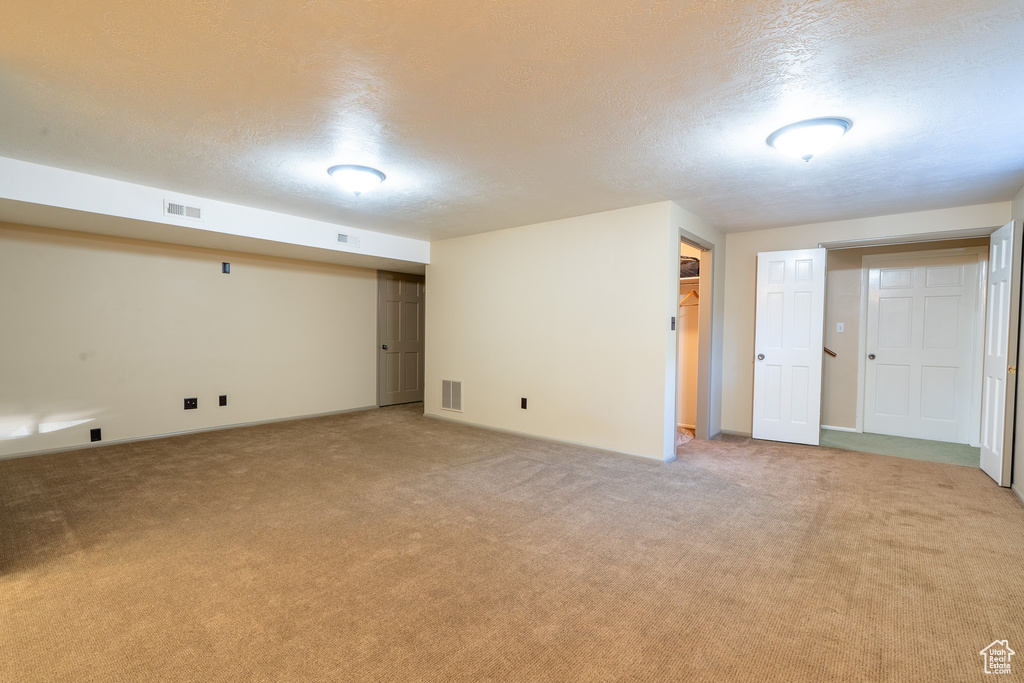 Basement featuring a textured ceiling and light colored carpet