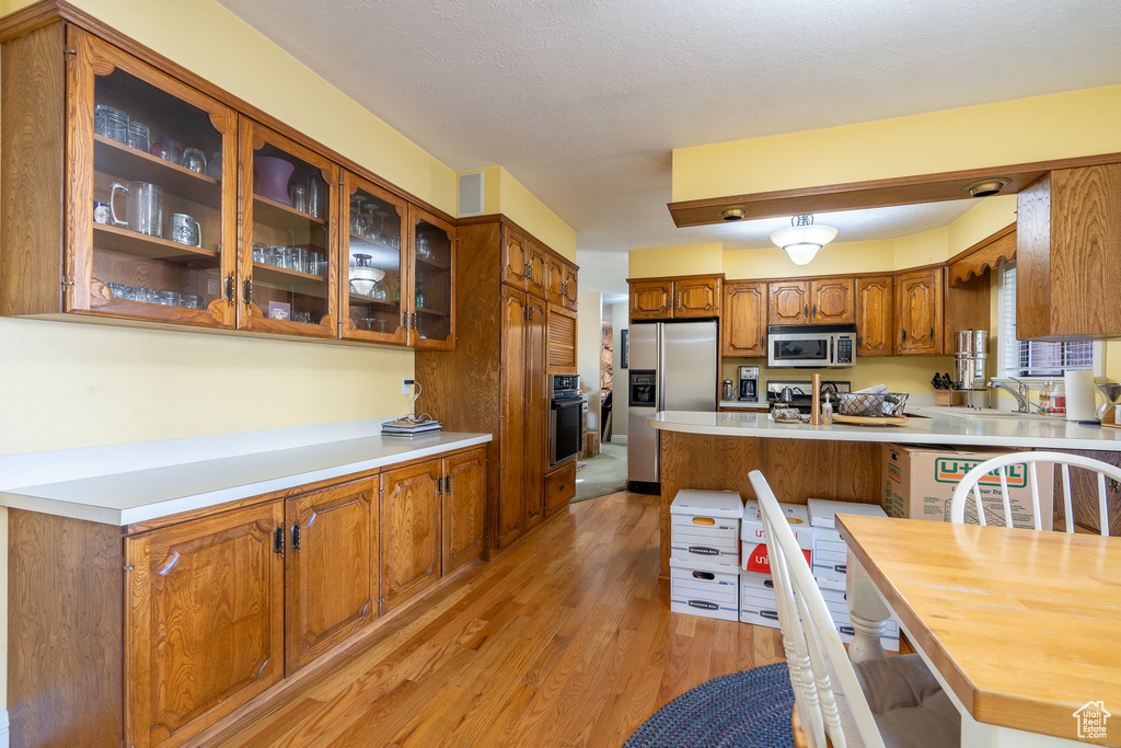 Kitchen featuring sink, appliances with stainless steel finishes, a textured ceiling, and light hardwood / wood-style floors