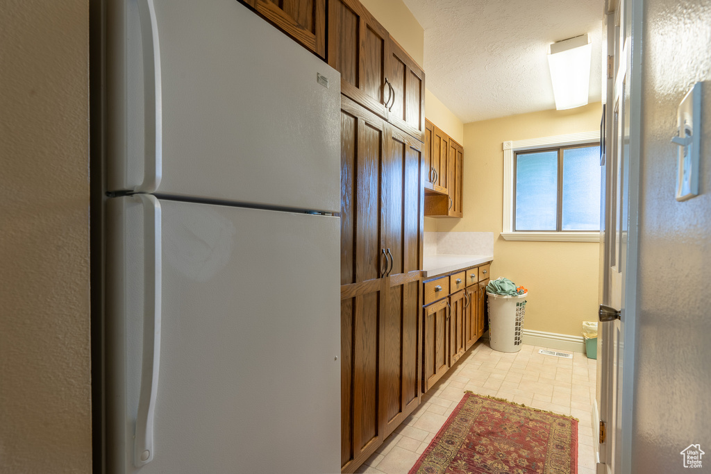 Kitchen featuring a textured ceiling, light tile patterned floors, and white refrigerator