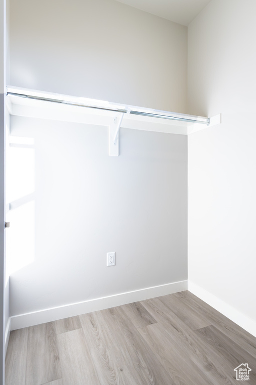 Walk in closet with light hardwood / wood-style flooring