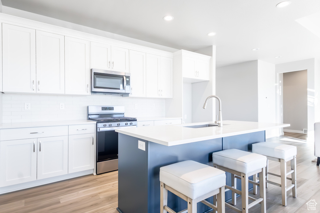 Kitchen with a sink, white cabinetry, appliances with stainless steel finishes, and a center island with sink