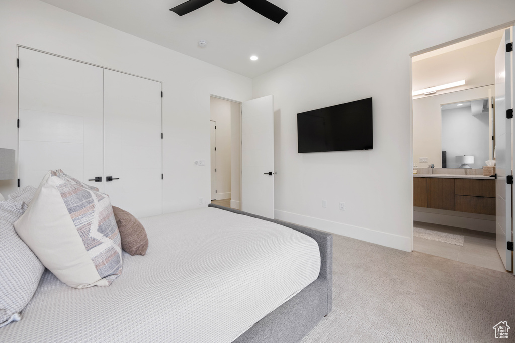 Carpeted bedroom with a closet, connected bathroom, and ceiling fan