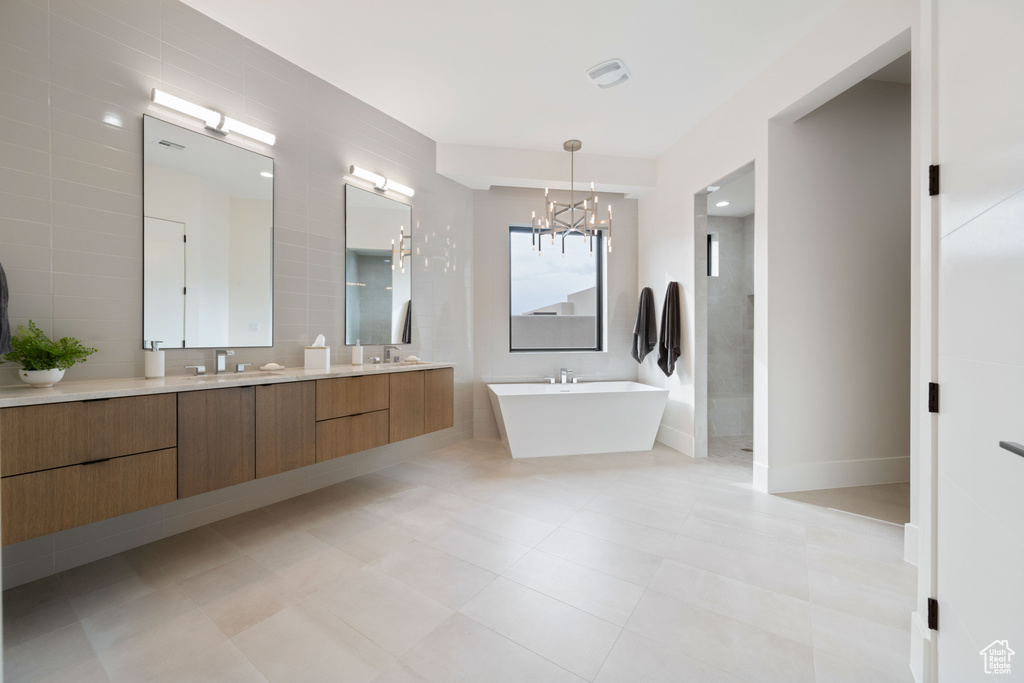 Bathroom featuring a chandelier, tile walls, a washtub, vanity, and tile patterned flooring