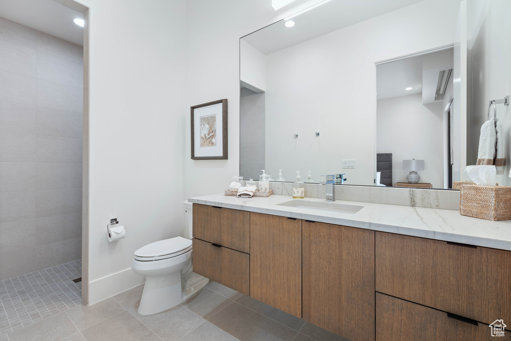 Bathroom with vanity, a tile shower, toilet, and tile patterned floors