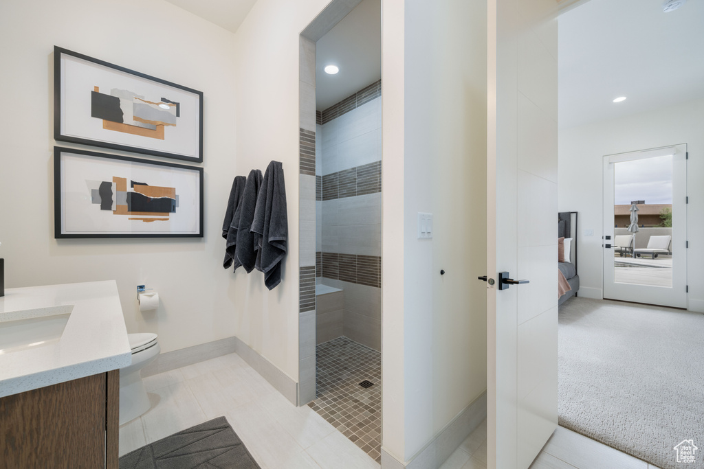 Bathroom featuring vanity, tiled shower, toilet, and tile patterned floors