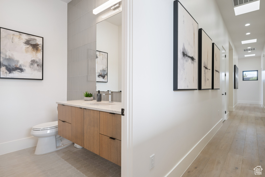 Bathroom featuring vanity, toilet, and wood-type flooring