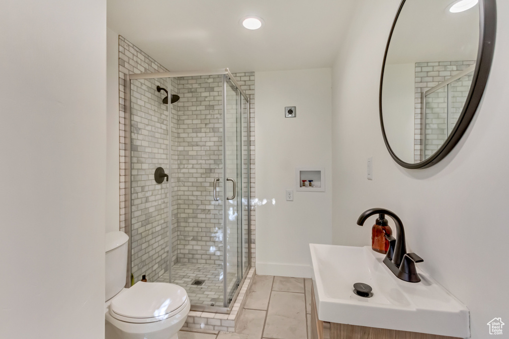 Bathroom featuring toilet, an enclosed shower, vanity, and tile patterned flooring