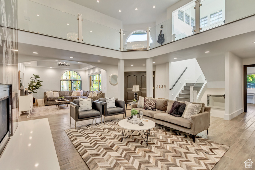 Living room featuring a high ceiling, light wood-type flooring, and plenty of natural light