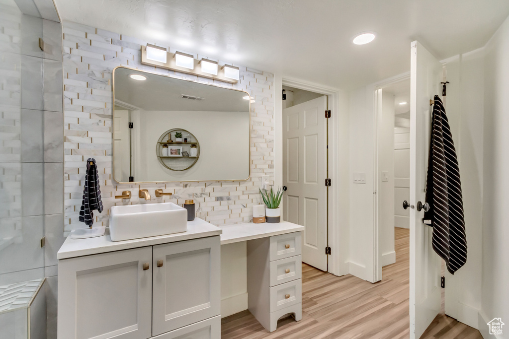 Bathroom featuring vanity, tasteful backsplash, wood-type flooring, and radiator heating unit