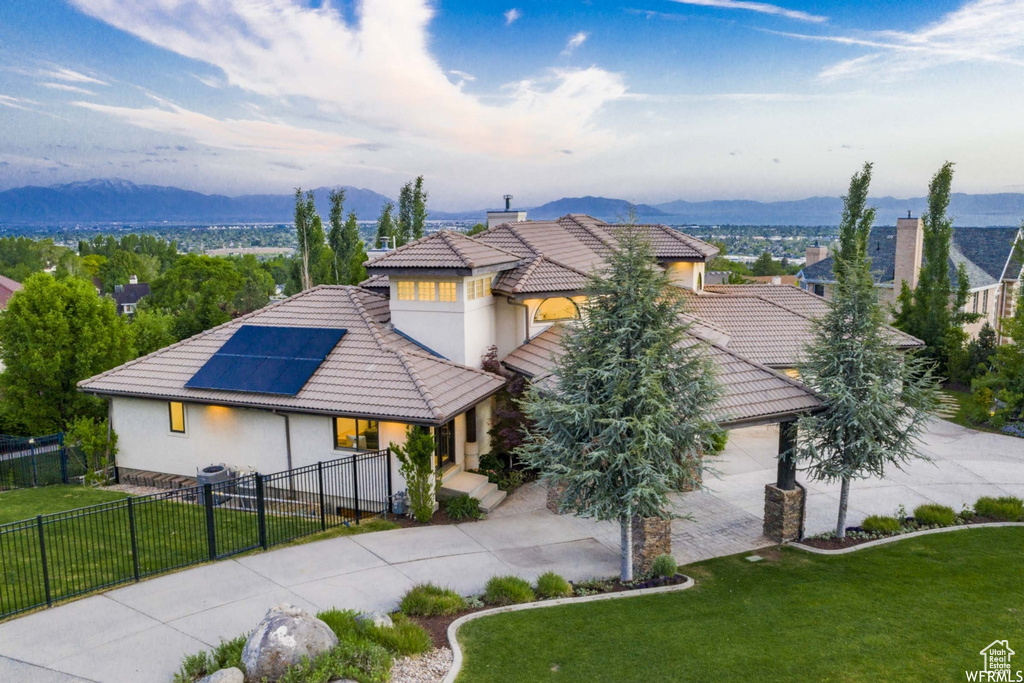 View of front of house featuring a front yard, solar panels, and a mountain view